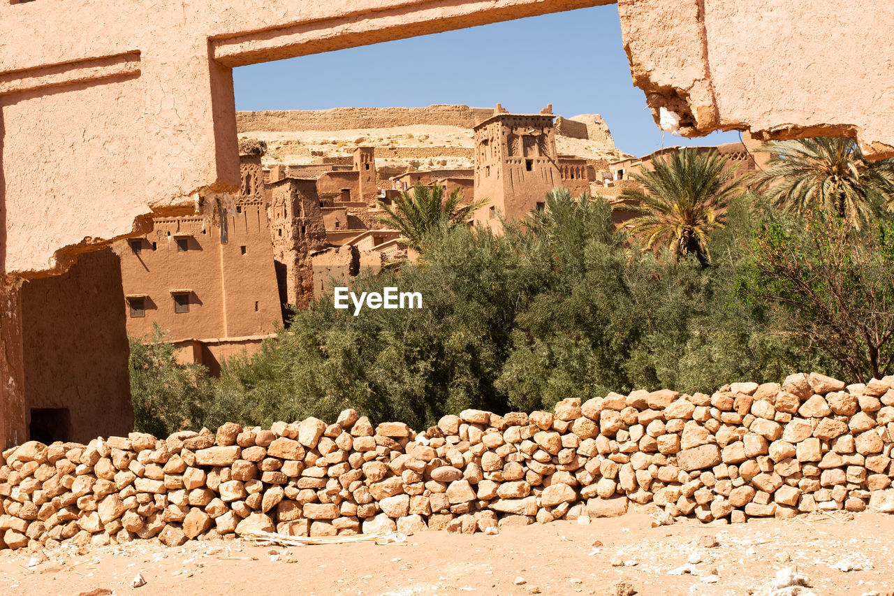 wall, architecture, ancient history, built structure, ruins, building exterior, nature, building, history, rock, tree, plant, no people, day, the past, wadi, sunlight, ancient, outdoors, old ruin, wall - building feature, travel destinations, house, stone wall, land, sky, stone material, village, desert, travel, temple, fortification, sunny, residential district, palm tree, clear sky