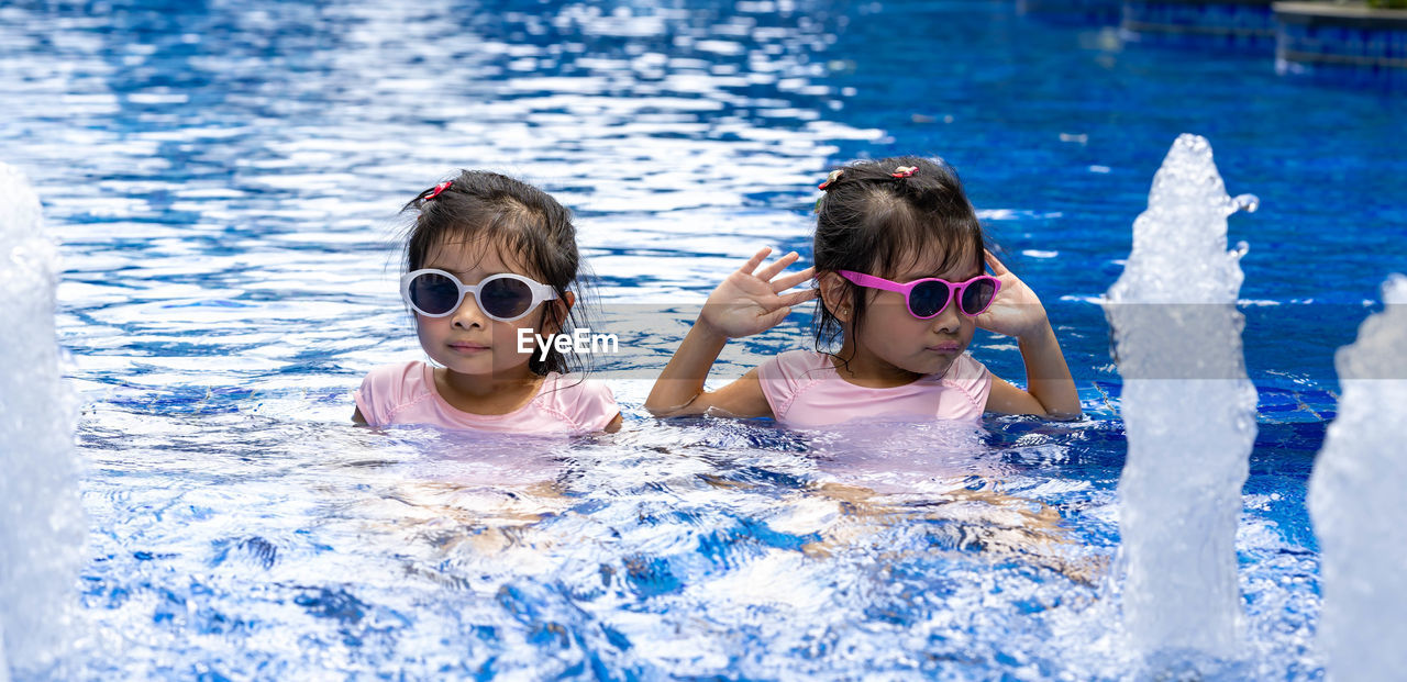 PORTRAIT OF SIBLINGS SWIMMING IN POOL