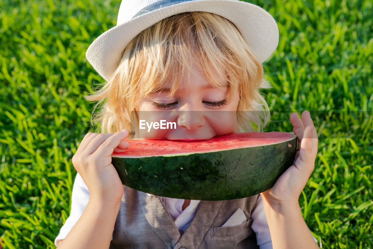 Boy holding watermelon on field