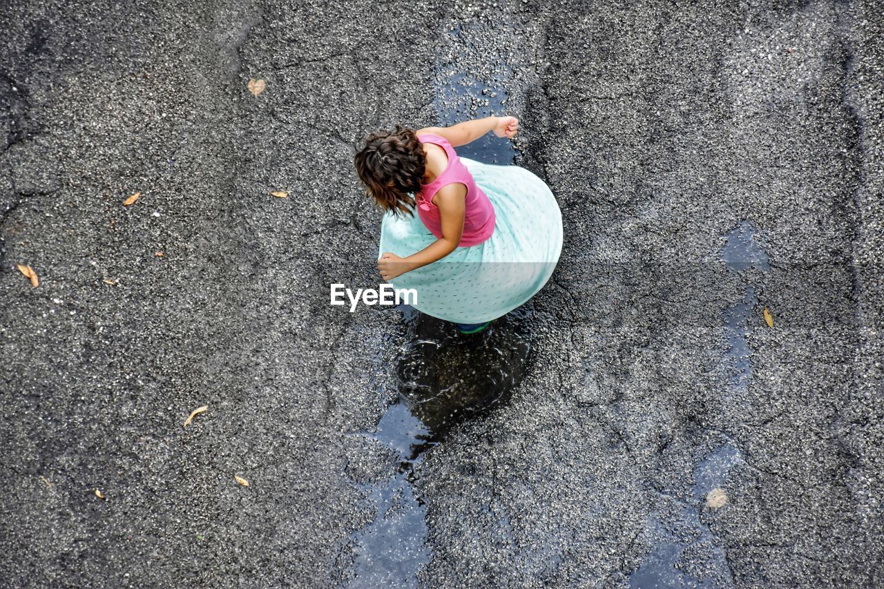 High angle view of girl playing on puddle at road