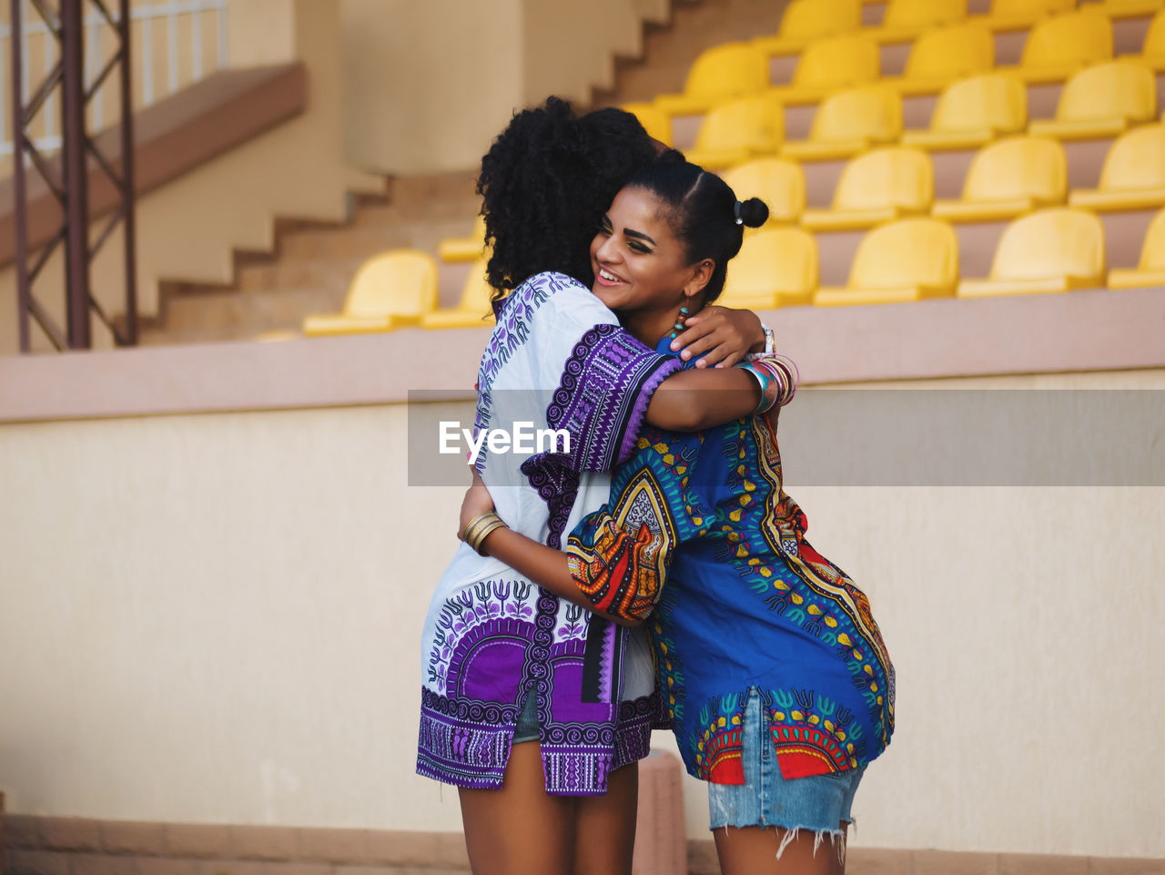 Young female friends embracing against stadium