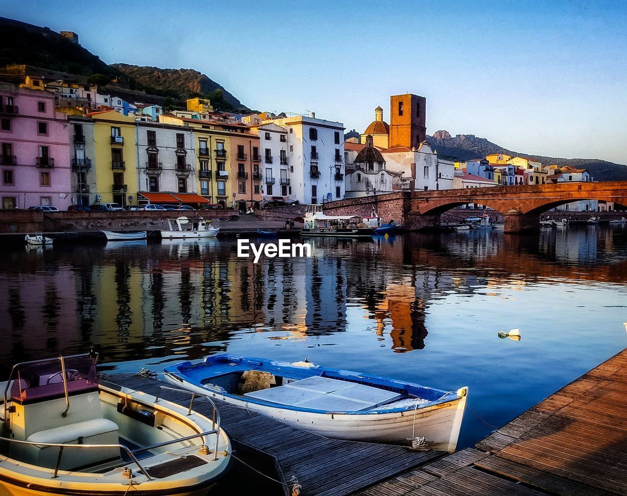 Sailboats moored on river by buildings in city against sky