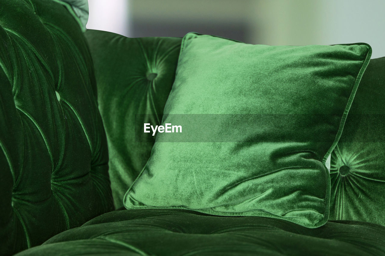 Green velvet sofa with cushion at home