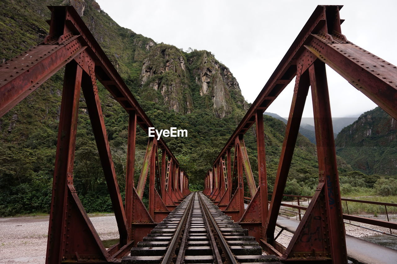 Railroad track by bridge against sky