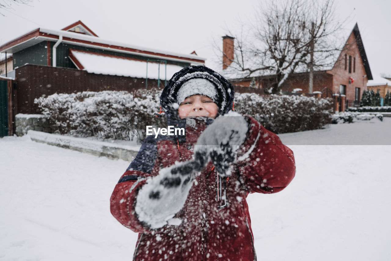 Close up outdoor winter portrait of boy playing snowballs. authentic, real, candid portrait of cute