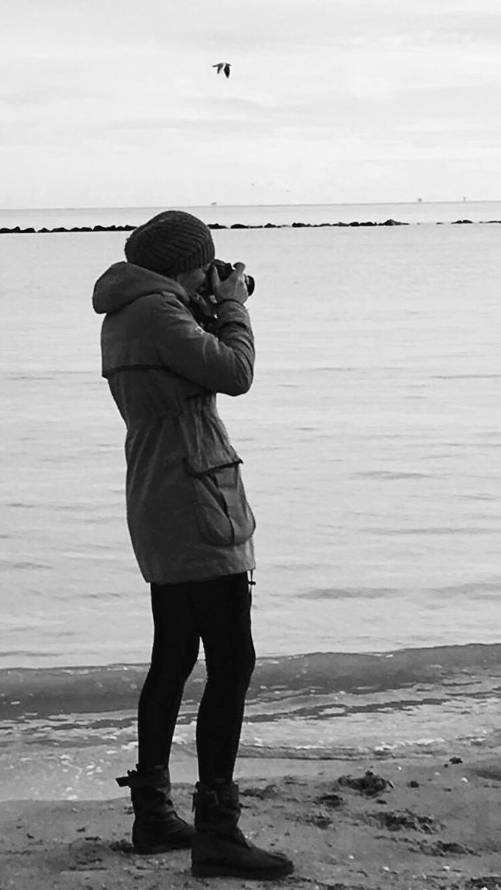 Side view of woman photographing at beach