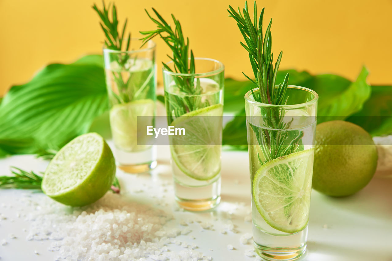 Drink with lime and rosemary on yellow background