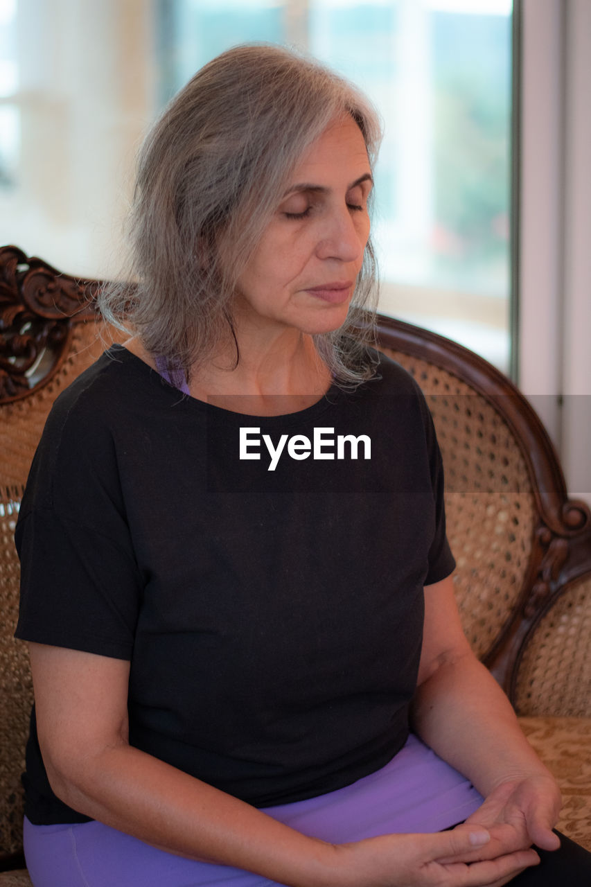 Senior woman with eyes closed sitting at home