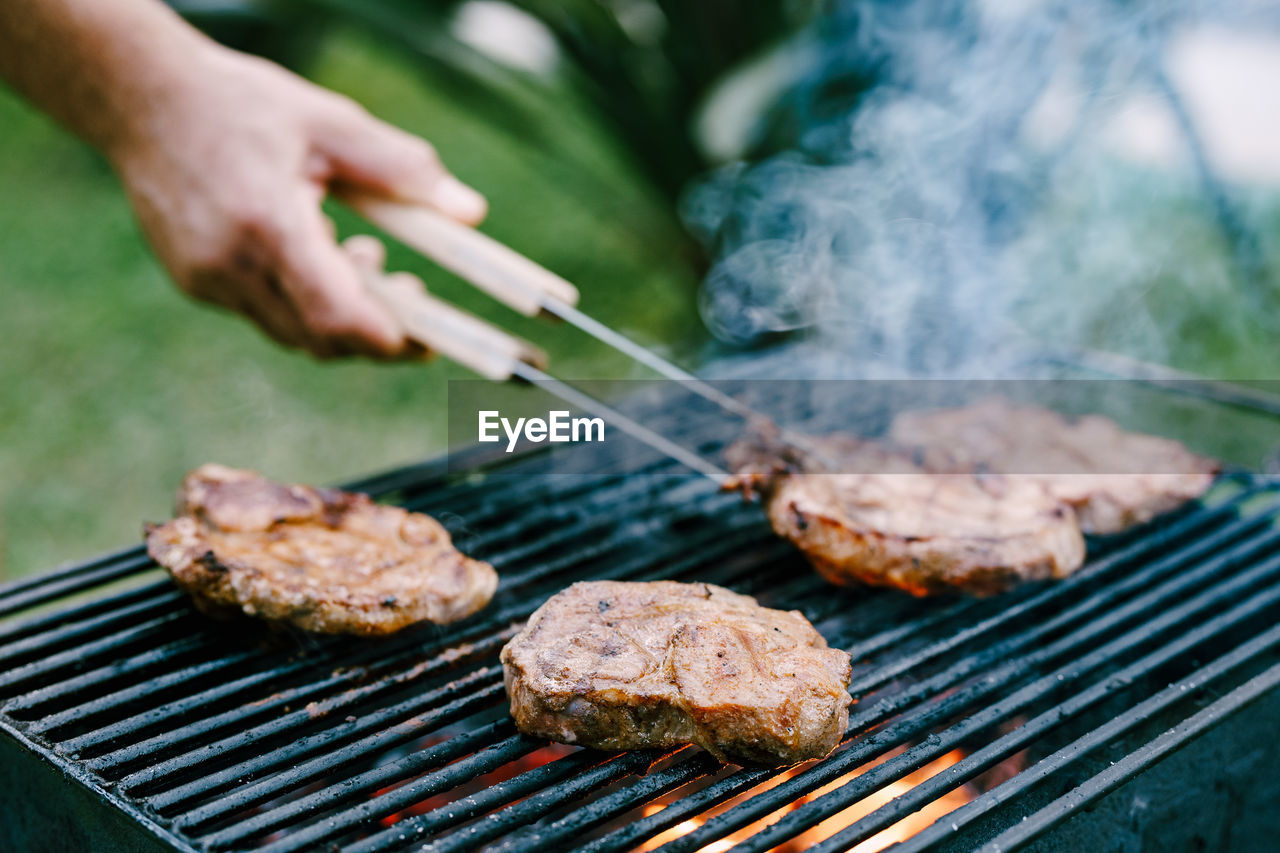 CLOSE-UP OF PREPARING MEAT ON BARBECUE GRILL