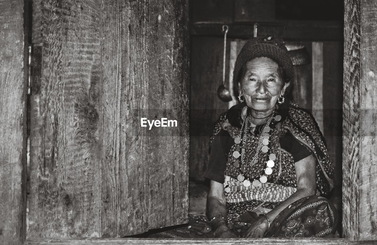 Portrait of smiling woman sitting on doorway