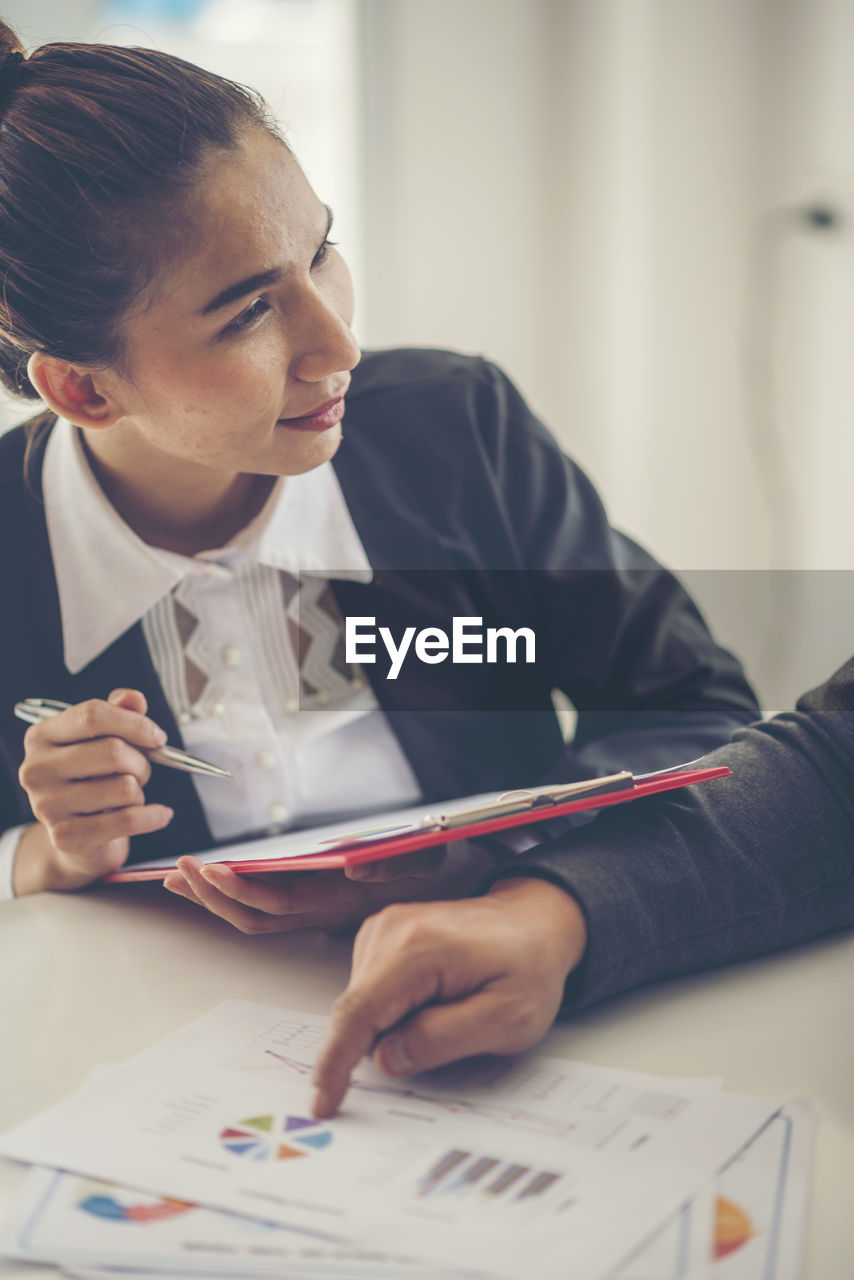 Cropped image of businessman discussing with businesswoman at desk in office