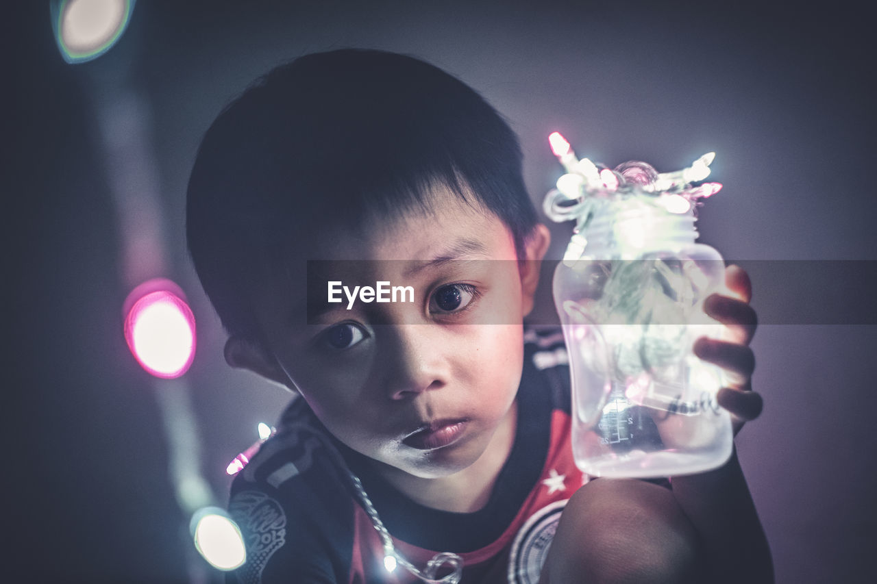 Close-up of boy holding jar of fairy lights