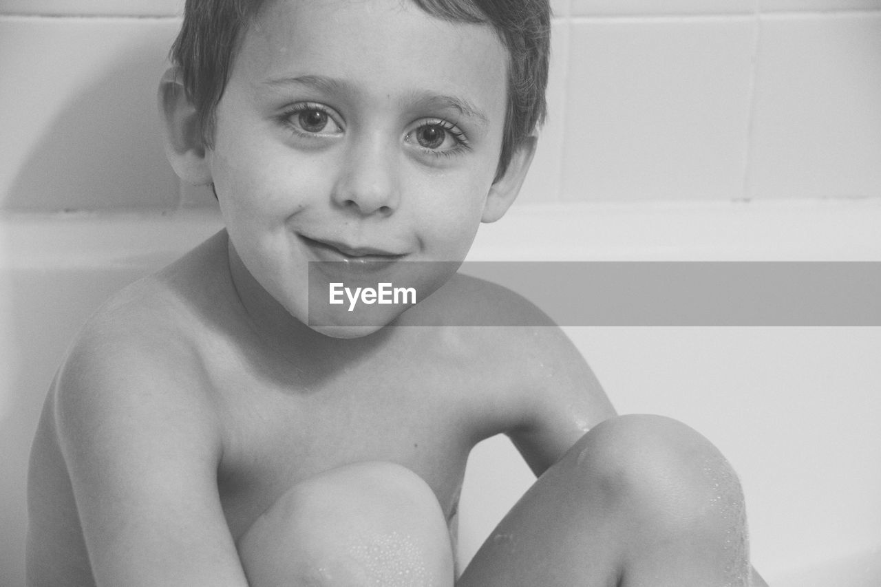 Portrait of smiling boy sitting in bathtub