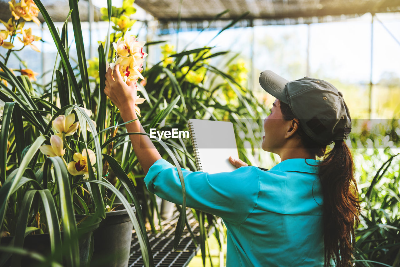 Female researcher examining flowers in greenhouse