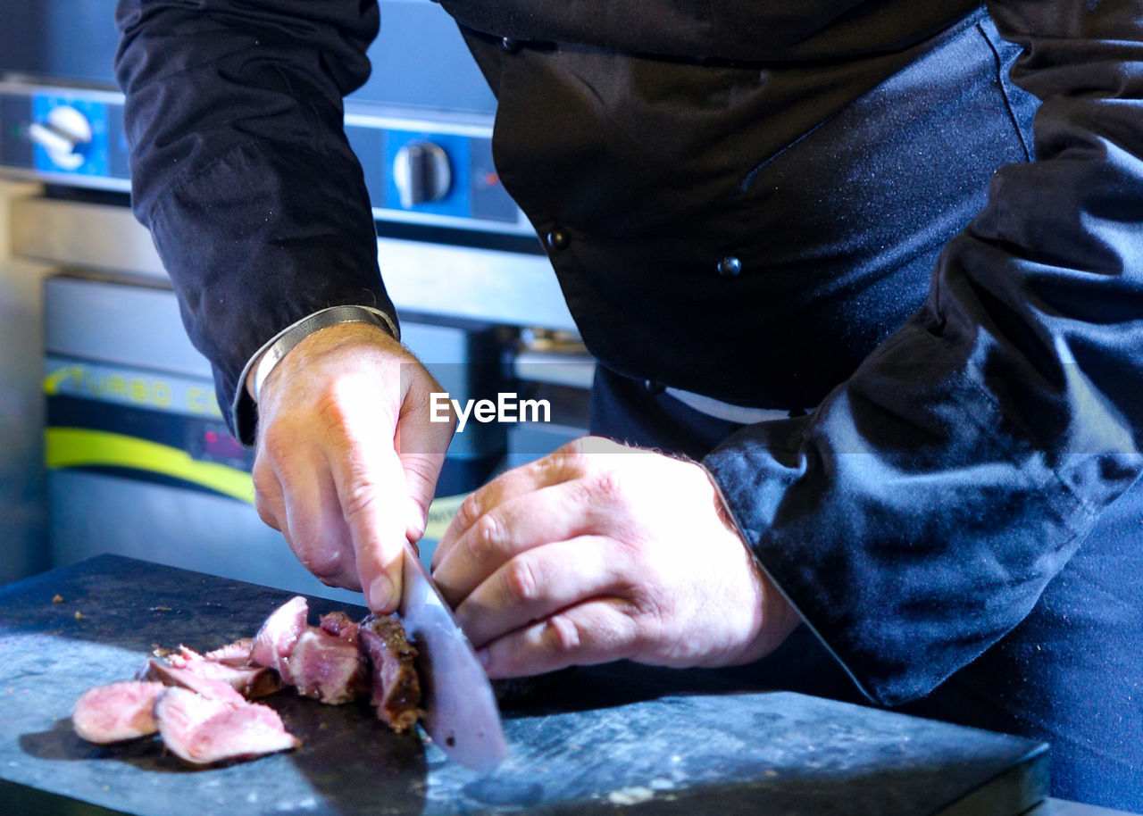 MIDSECTION OF MAN WORKING WITH MEAT IN COOKING