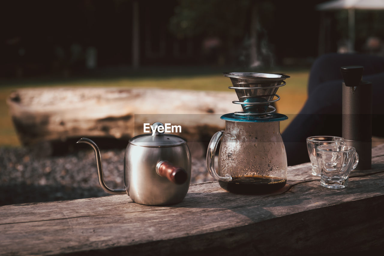 Coffee maker is placed on top of wooden chair in camping area.