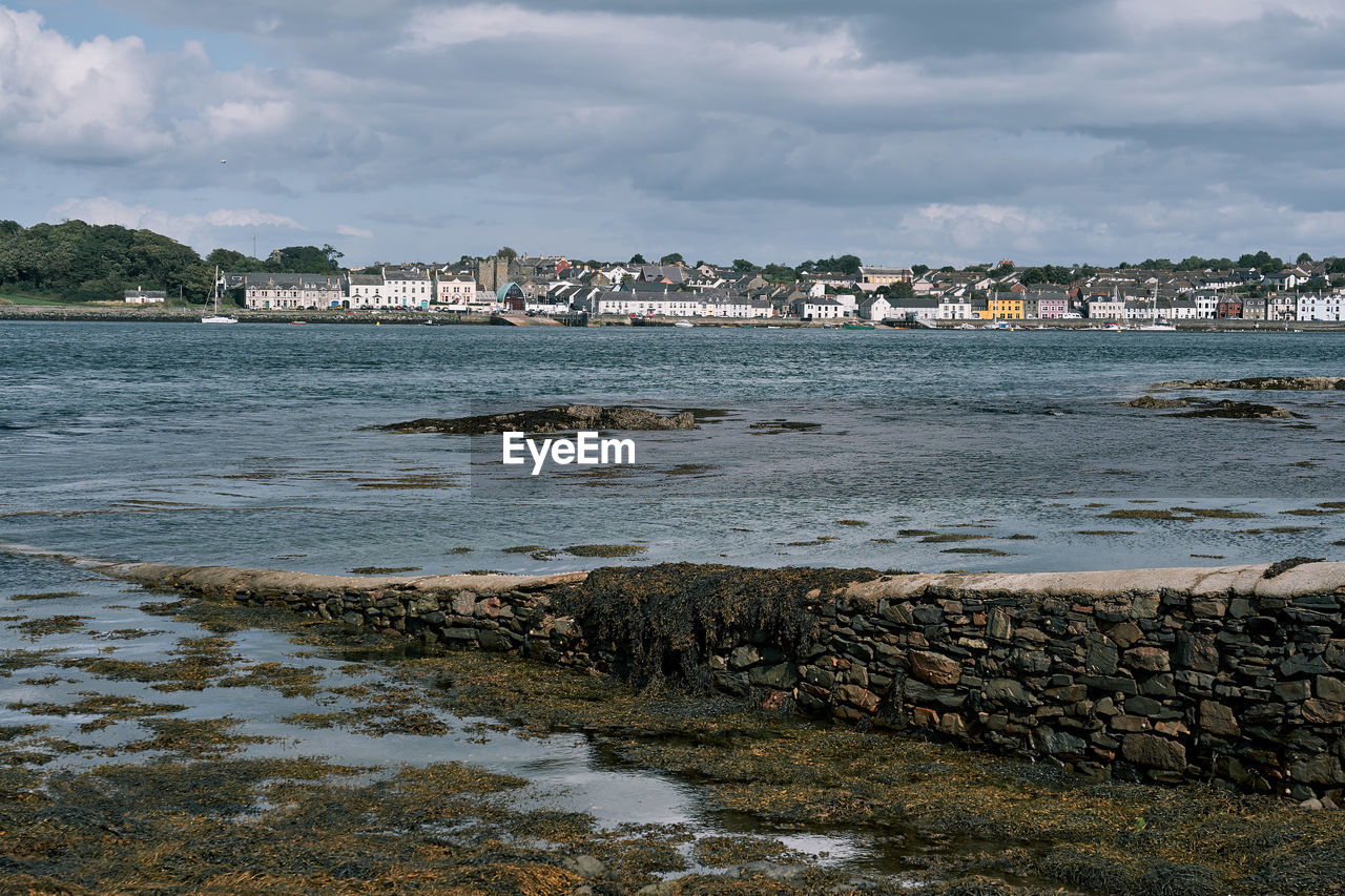 Scenic view of sea by buildings against sky