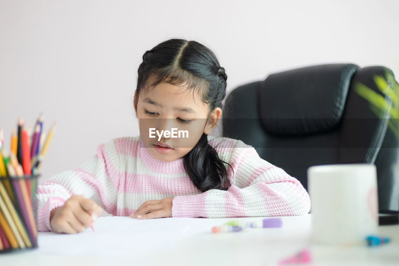 Girl writing in paper against white background