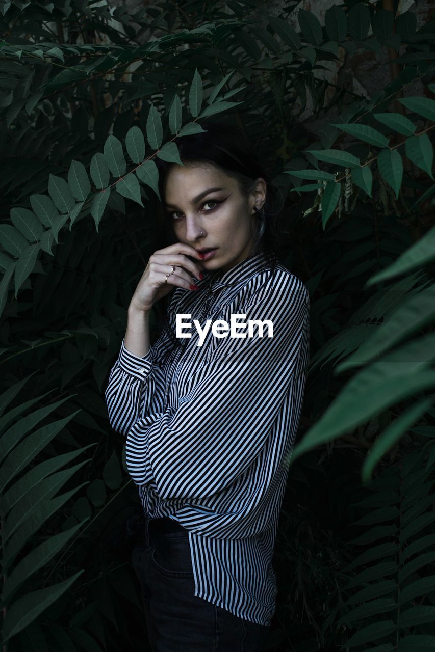 Portrait of young woman standing amidst plants