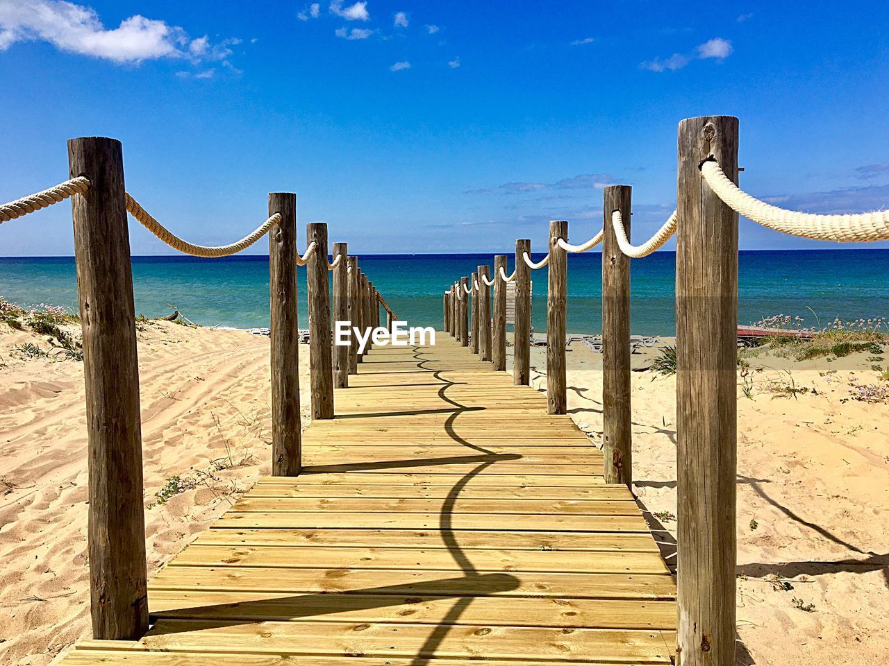 WOODEN POSTS IN SEA AGAINST SKY