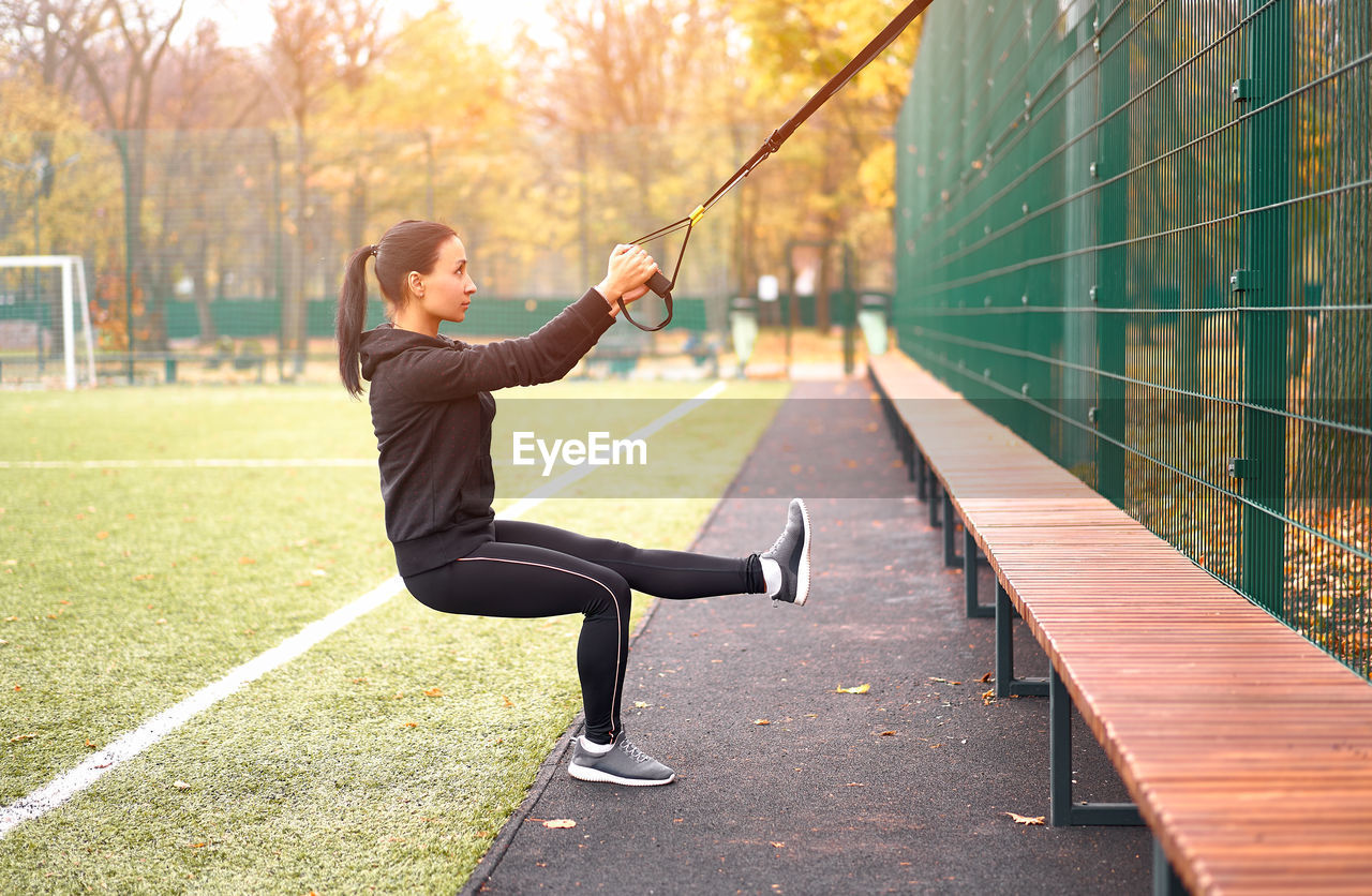 Side view of woman exercising with strap in public park