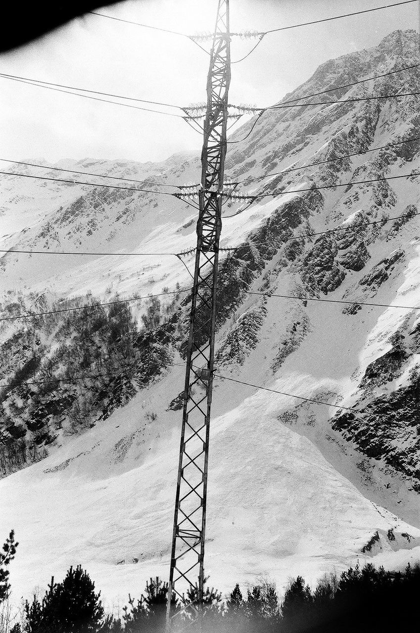 LOW ANGLE VIEW OF ELECTRICITY PYLON AGAINST MOUNTAINS