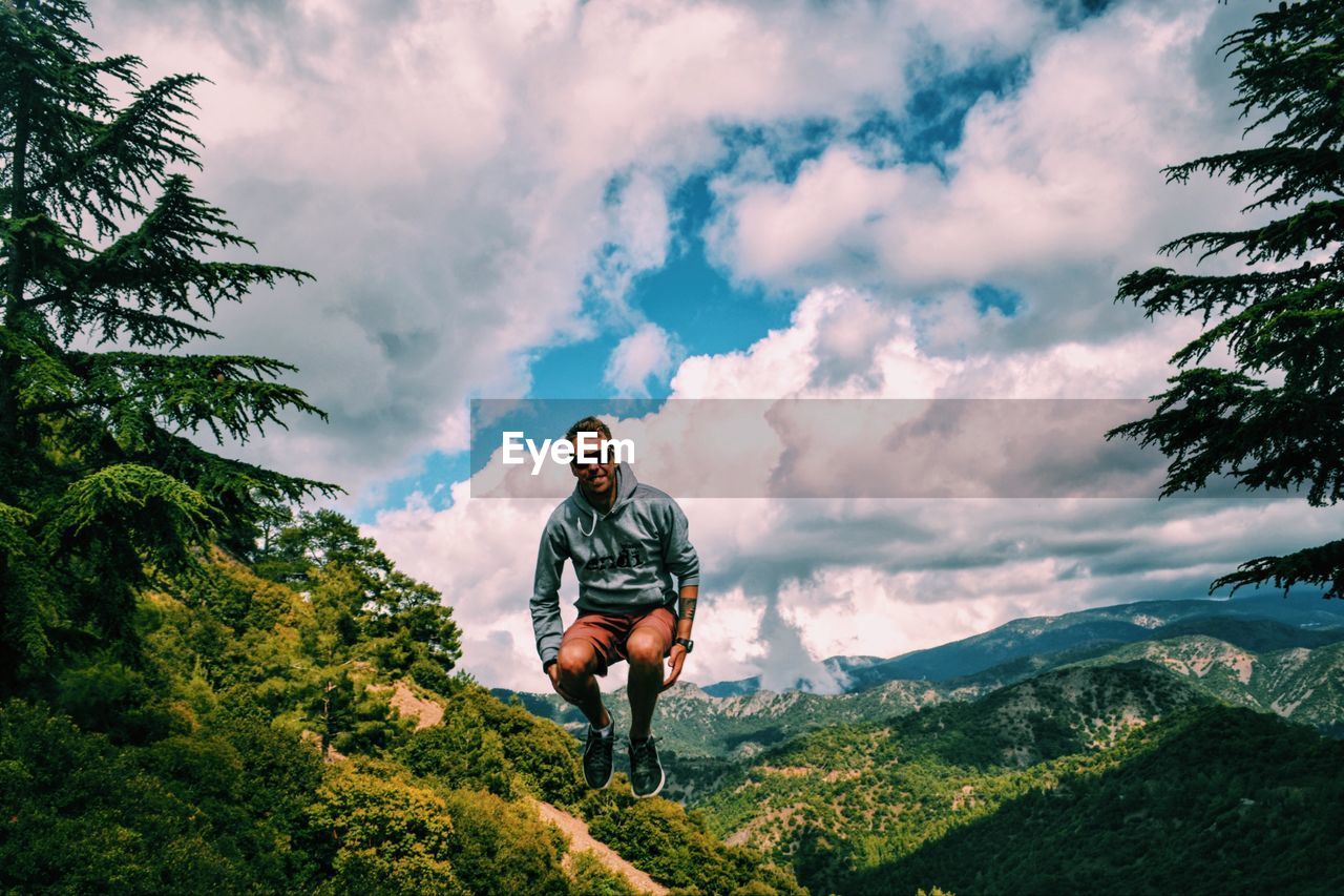 Full length of young man jumping against mountains