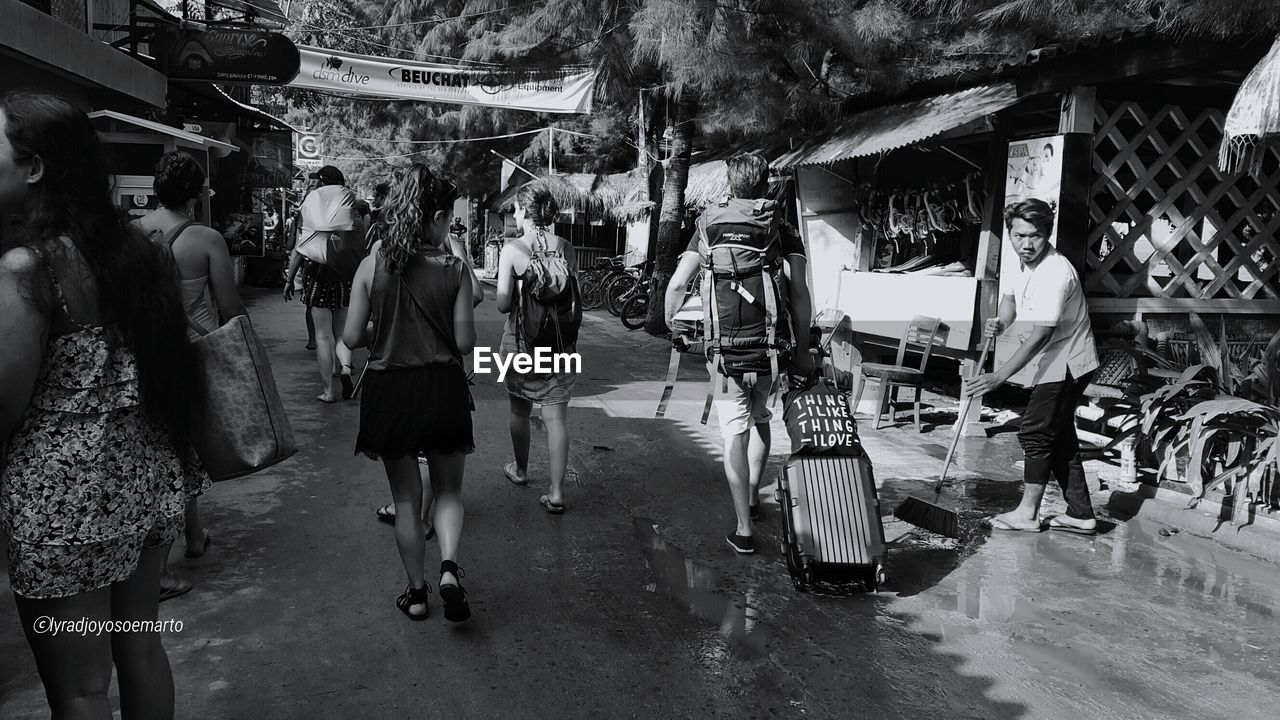 PEOPLE WALKING ON STREET AMIDST TREES