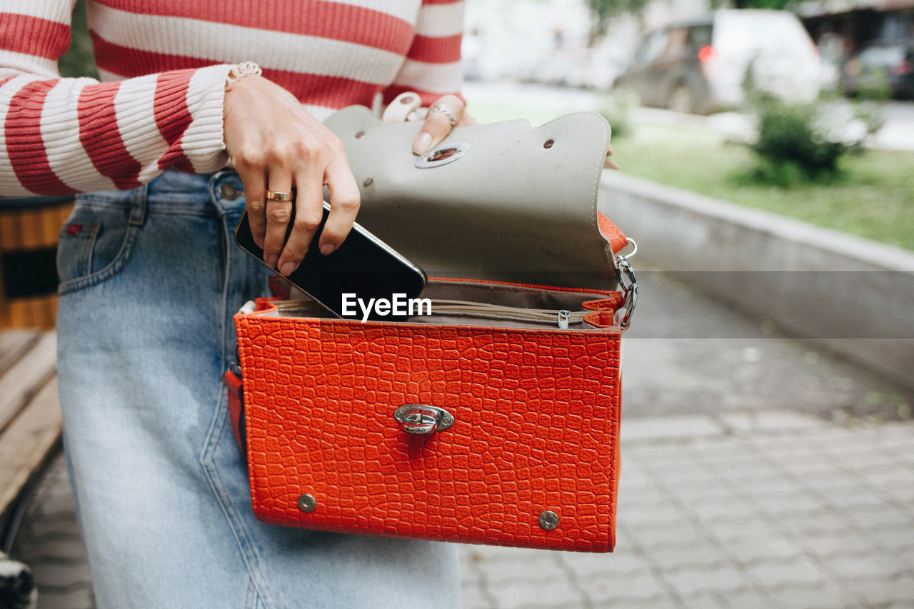 CLOSE-UP OF WOMAN HOLDING RED CAMERA ON HAND