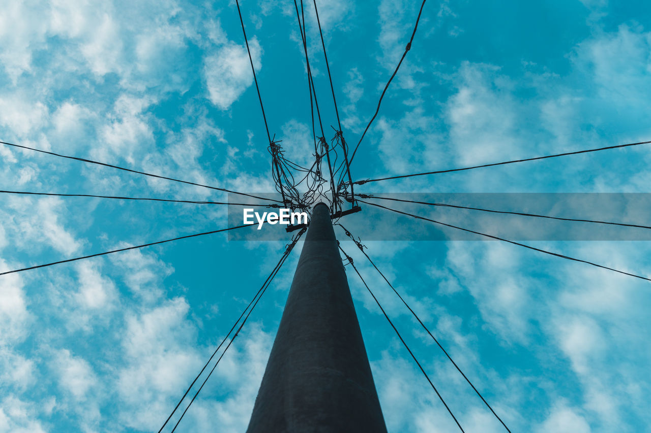 Low angle view of electricity pylon against blue sky