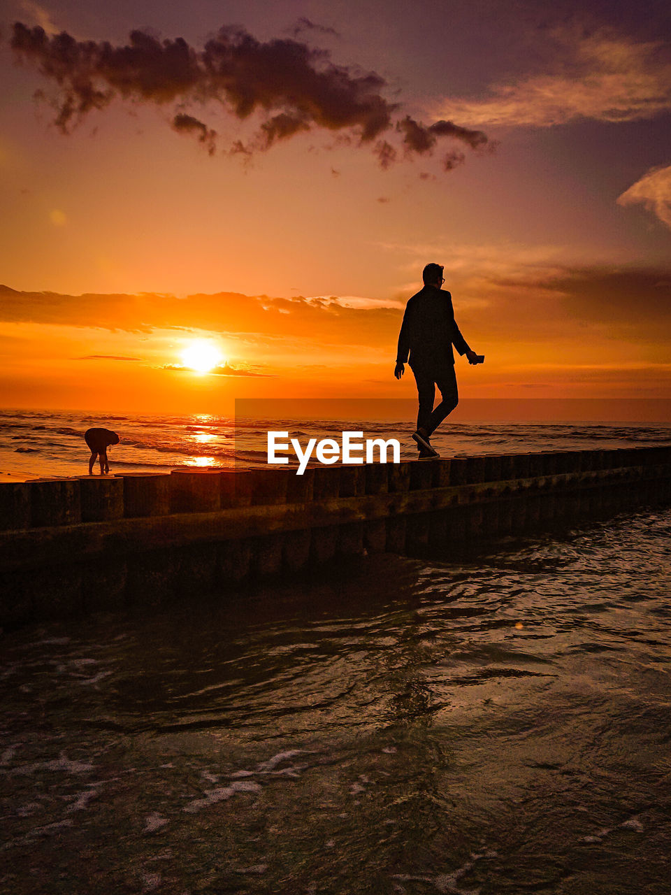 Silhouette man standing on beach against sky during sunset