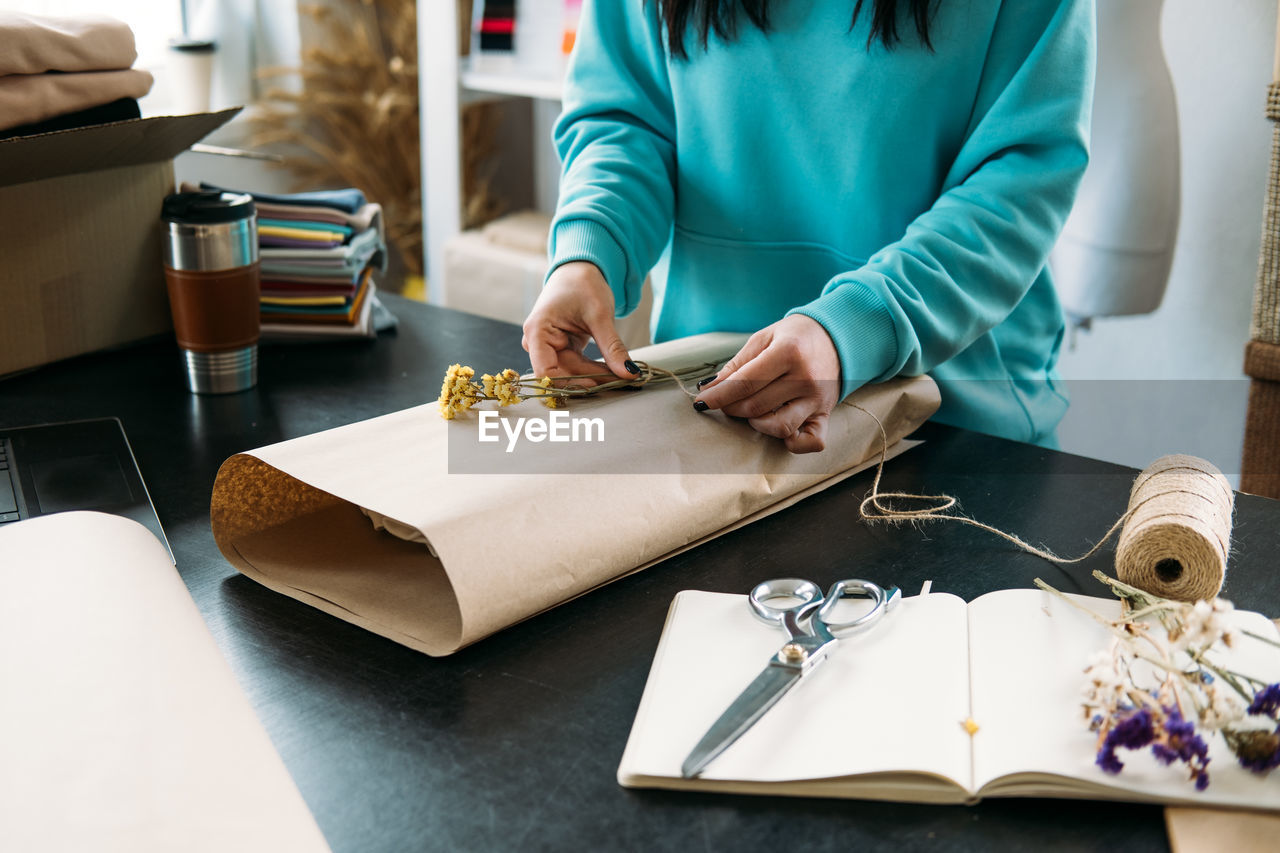 Small business owner woman packs the goods in eco packaging in office, shop.