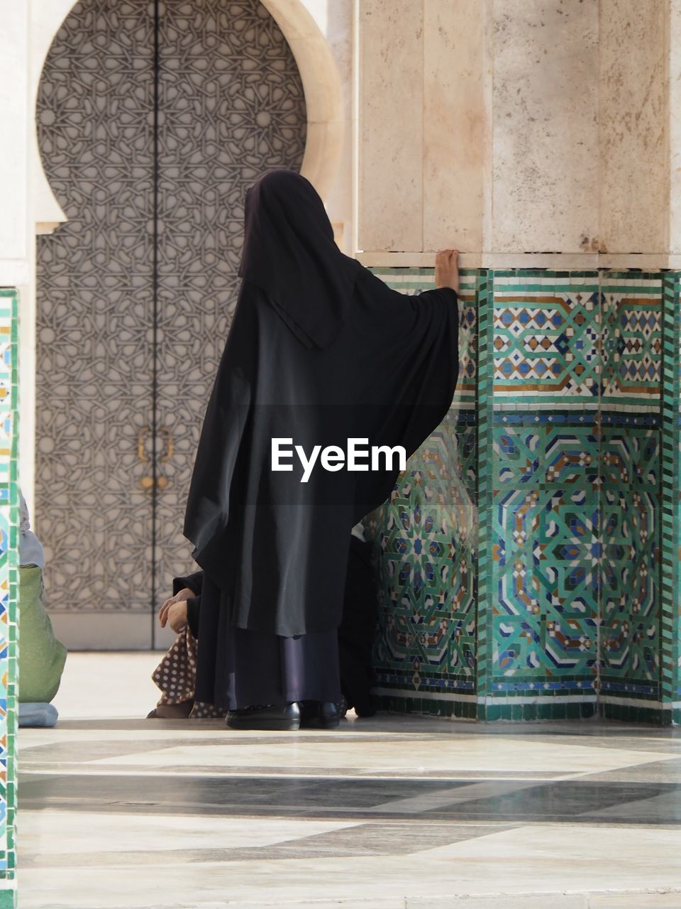 Woman in burkha standing by wall at mosque