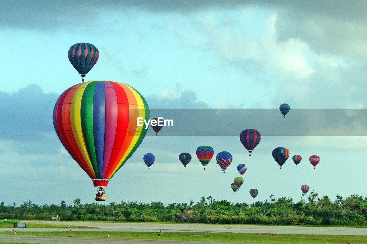 MULTI COLORED HOT AIR BALLOONS FLYING AGAINST SKY