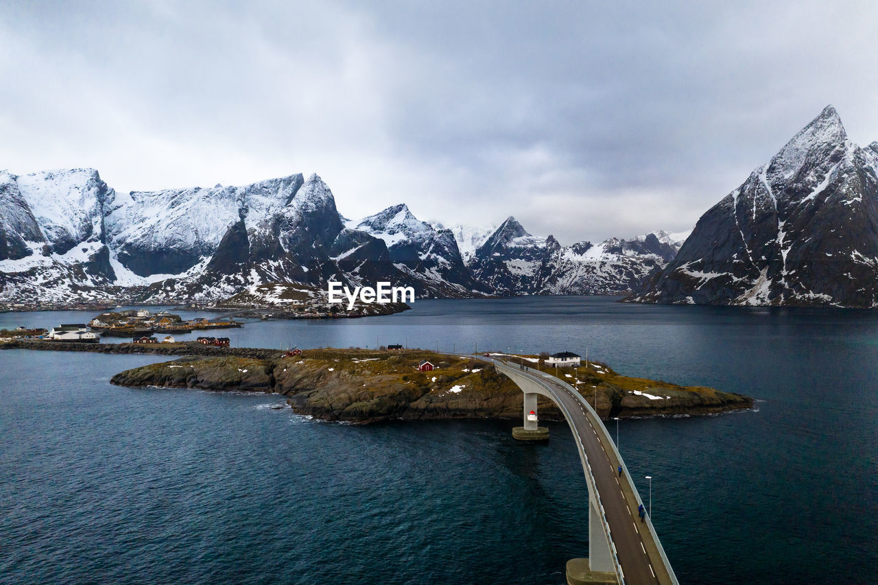 Scenic view of sea by snowcapped mountains against sky