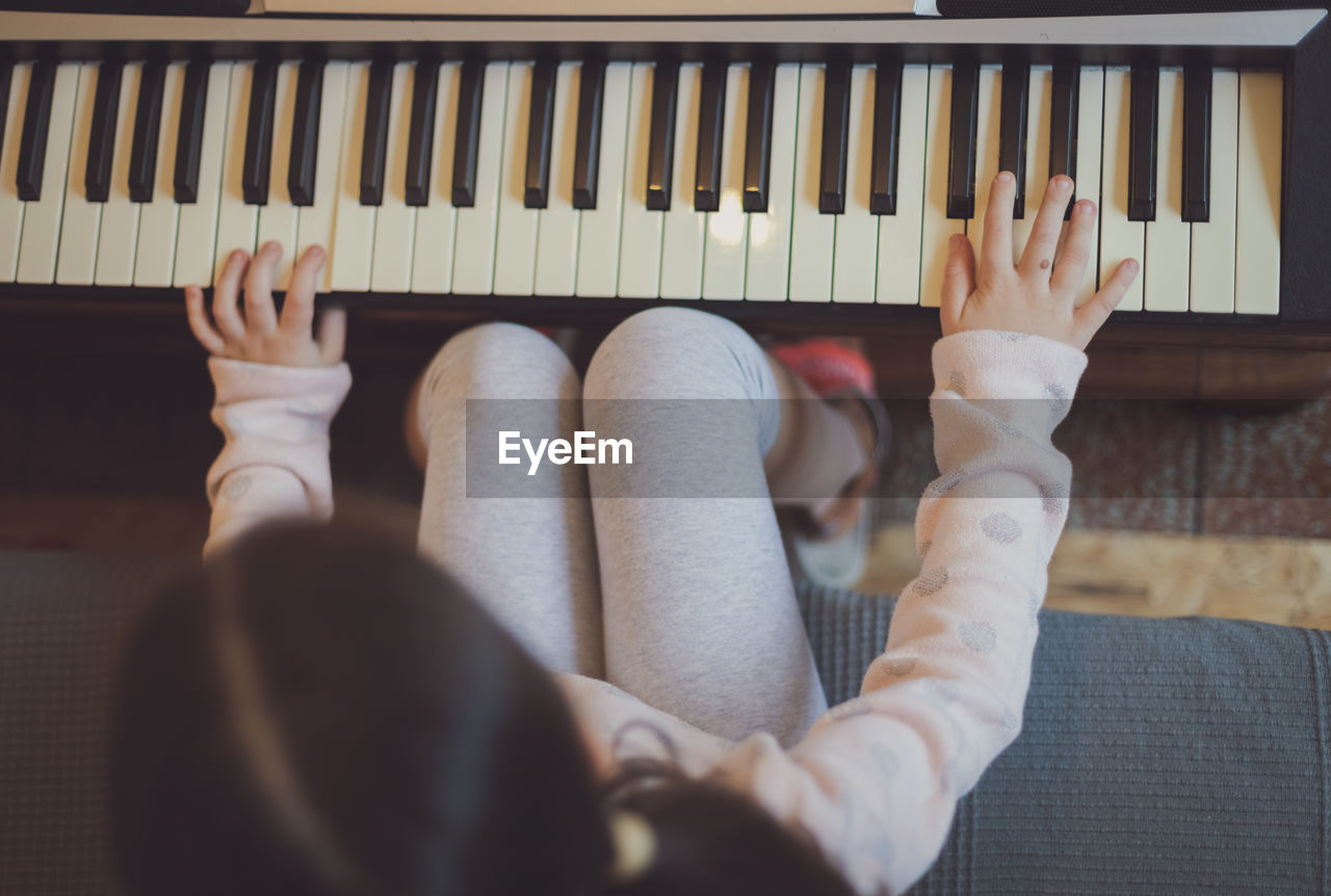 A little girl plays the electric piano.