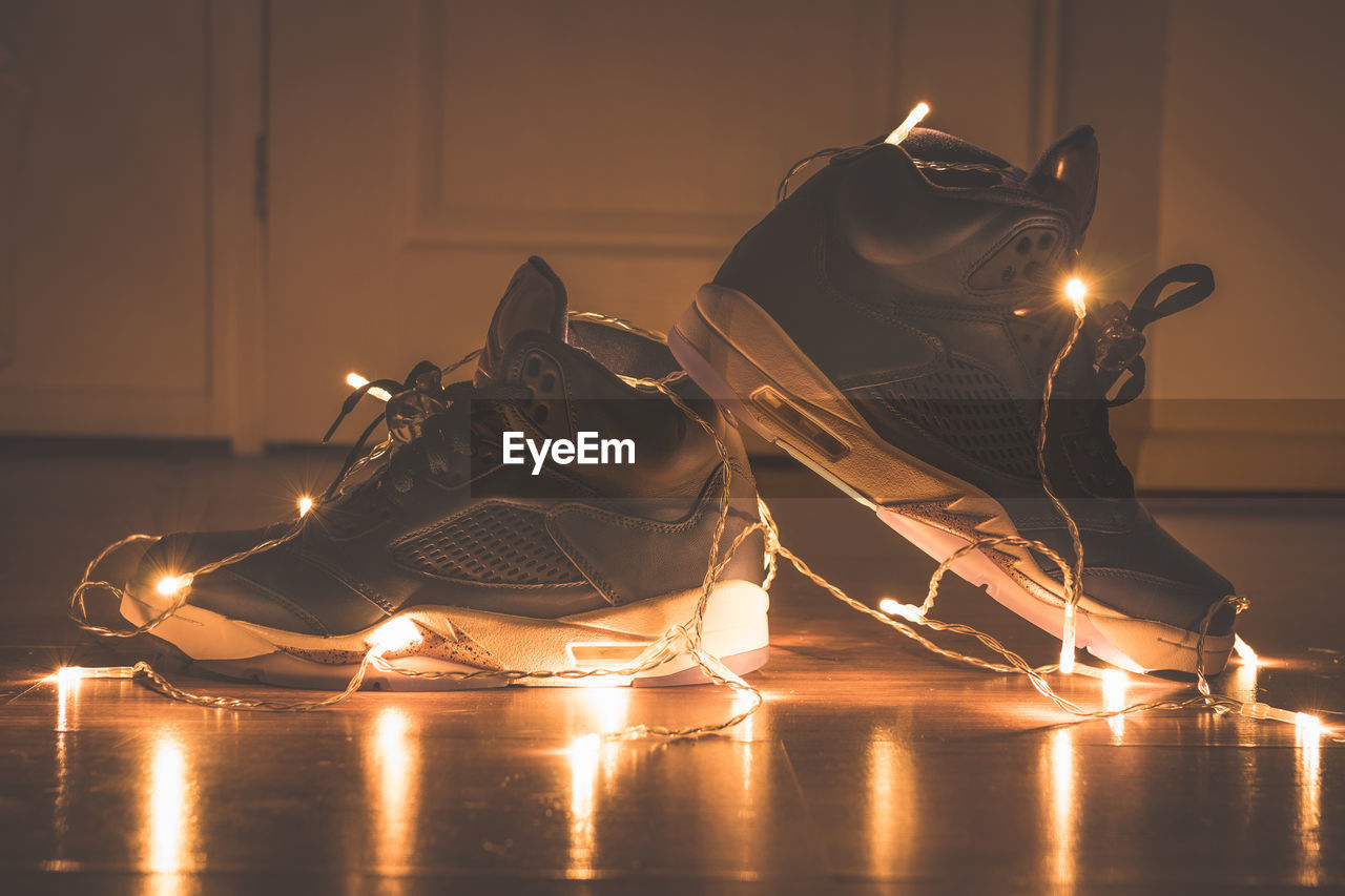 Shoes with illuminated string lights on floor at home