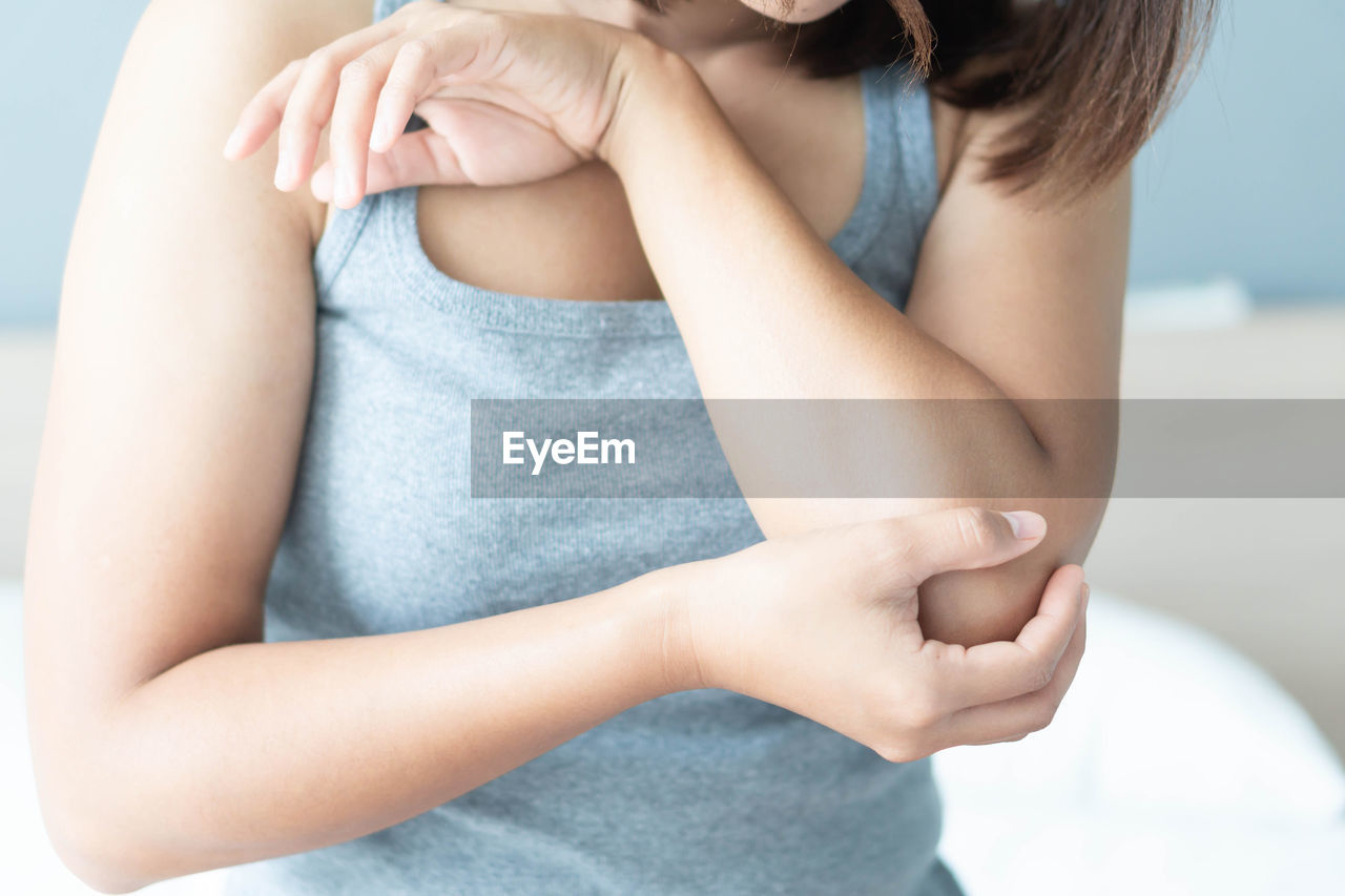 Midsection of woman suffering from elbow pain at home