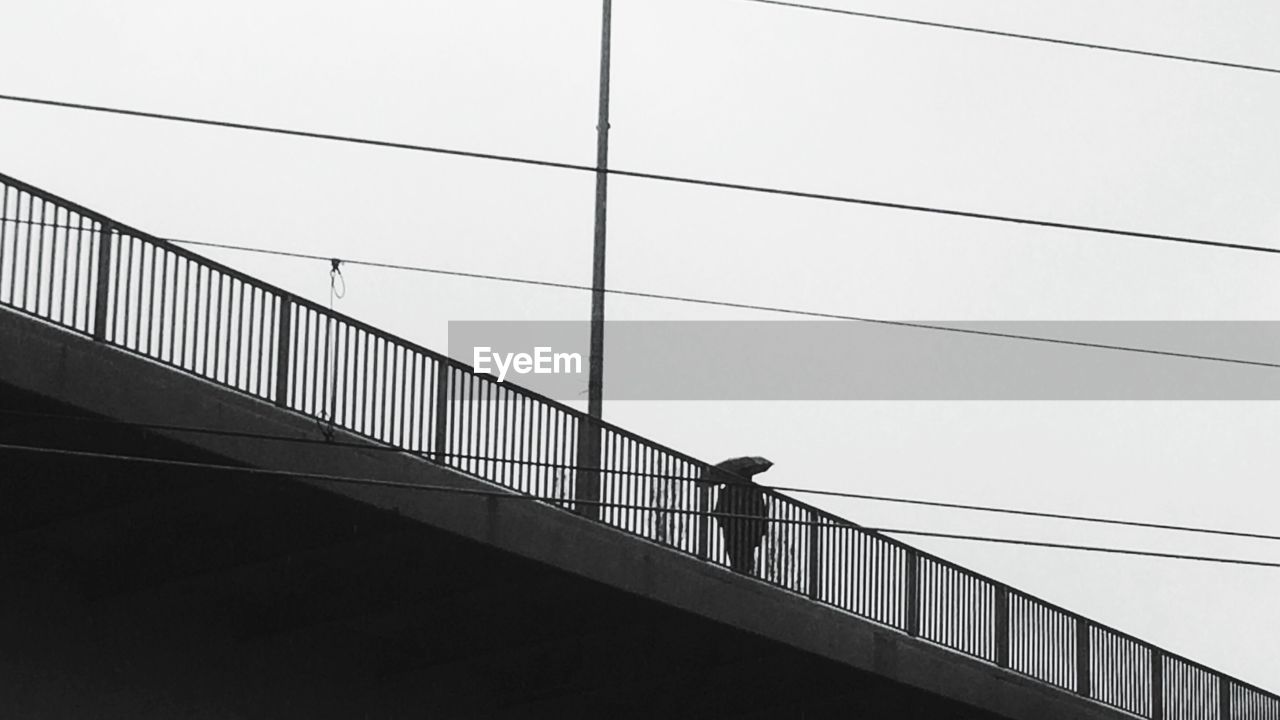 LOW ANGLE VIEW OF WOMAN STANDING ON RAILING