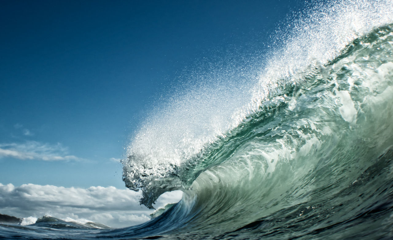 Close-up of wave rushing at shore against sky