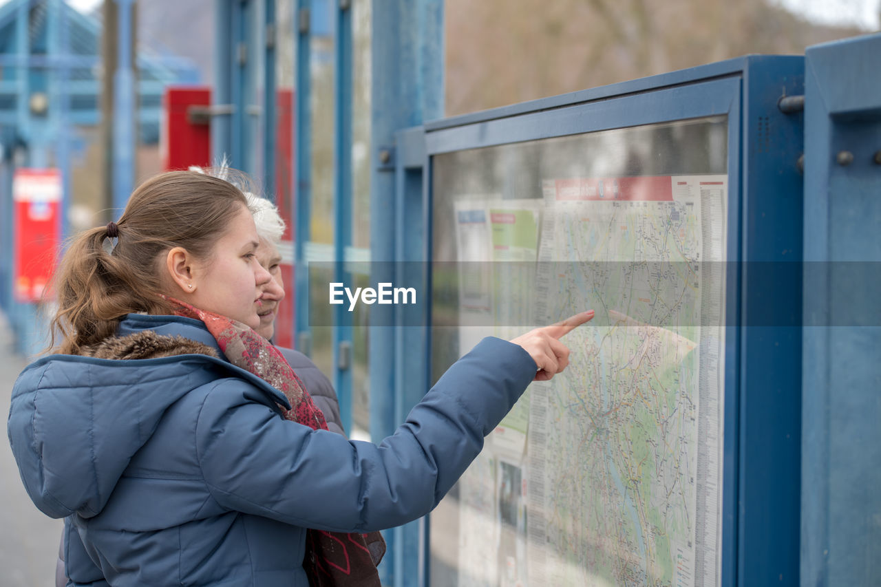 Granddaughter showing map to grandmother at railroad station platform