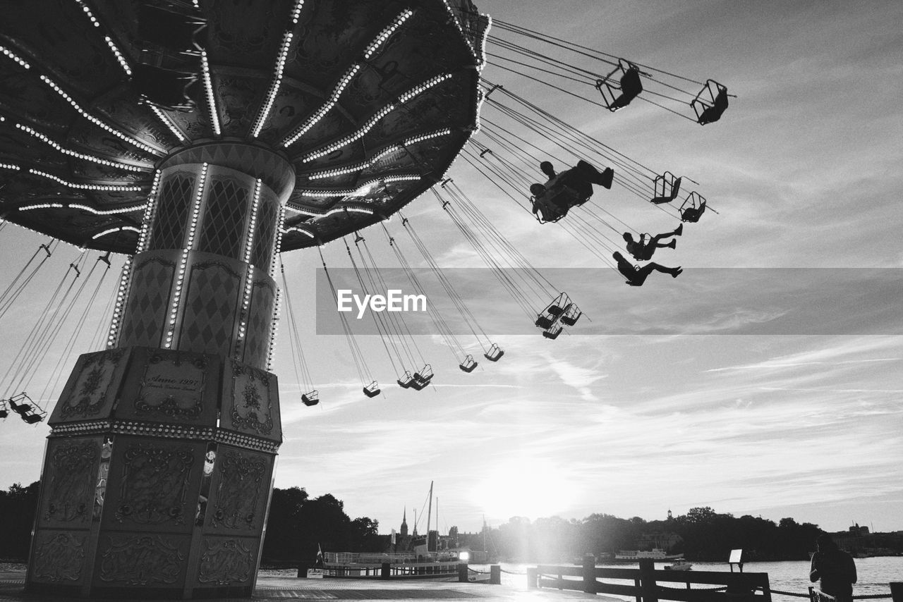 Low angle view of chain swing ride against sky