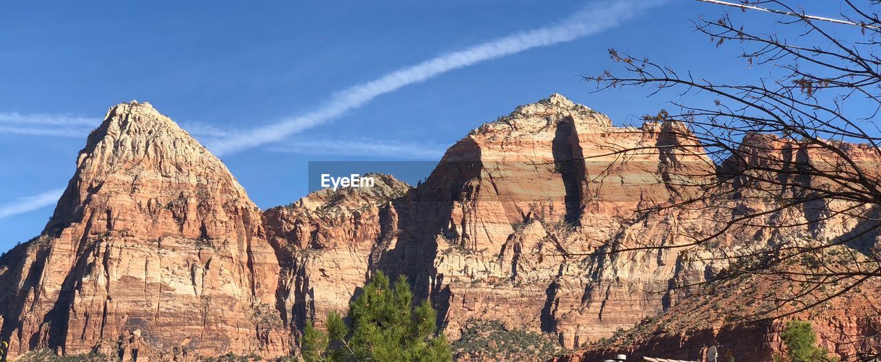 Low angle view of trees on mountain against blue sky