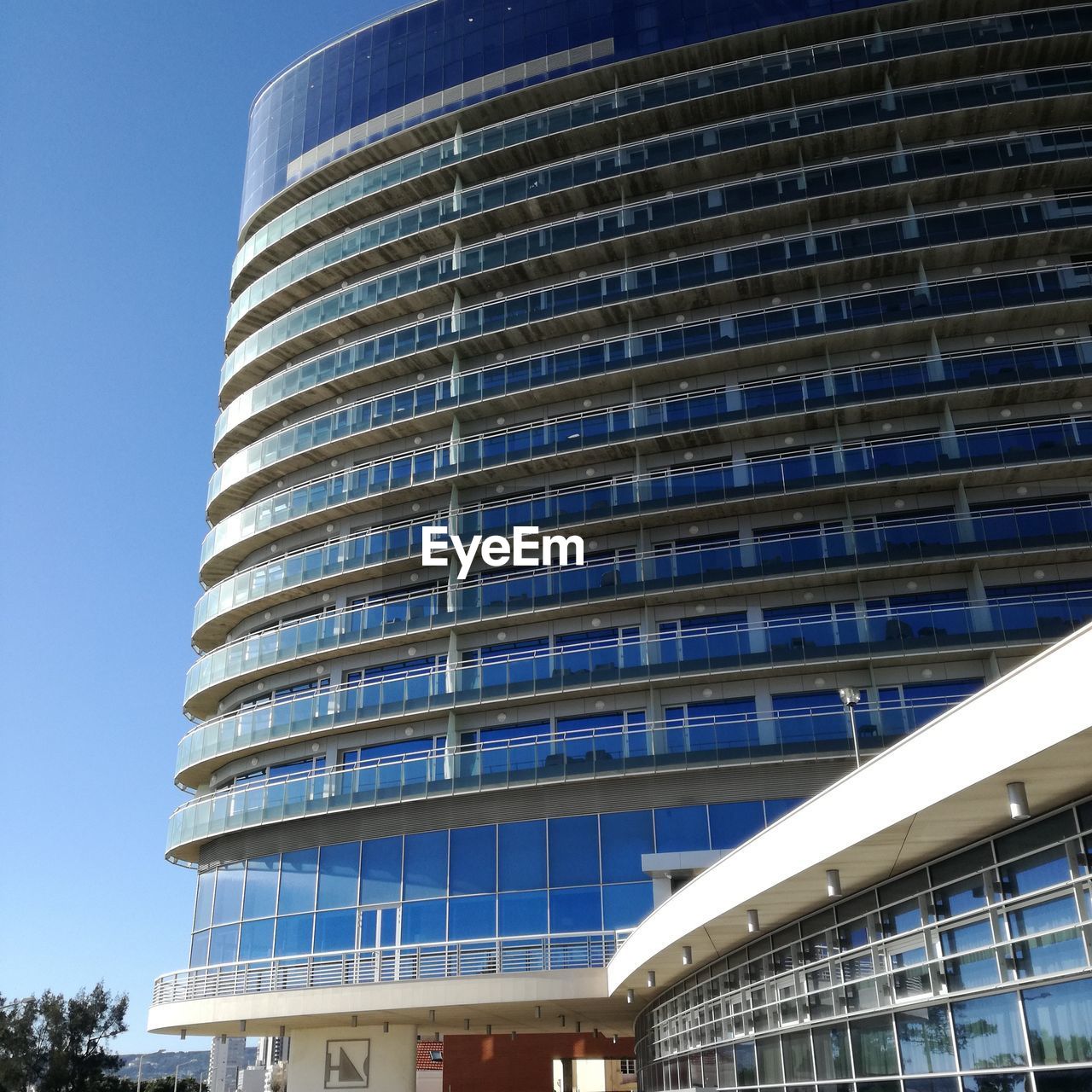 LOW ANGLE VIEW OF OFFICE BUILDING AGAINST BLUE SKY