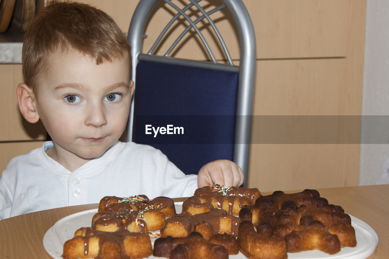 PORTRAIT OF BOY LOOKING AT ICE CREAM IN KITCHEN