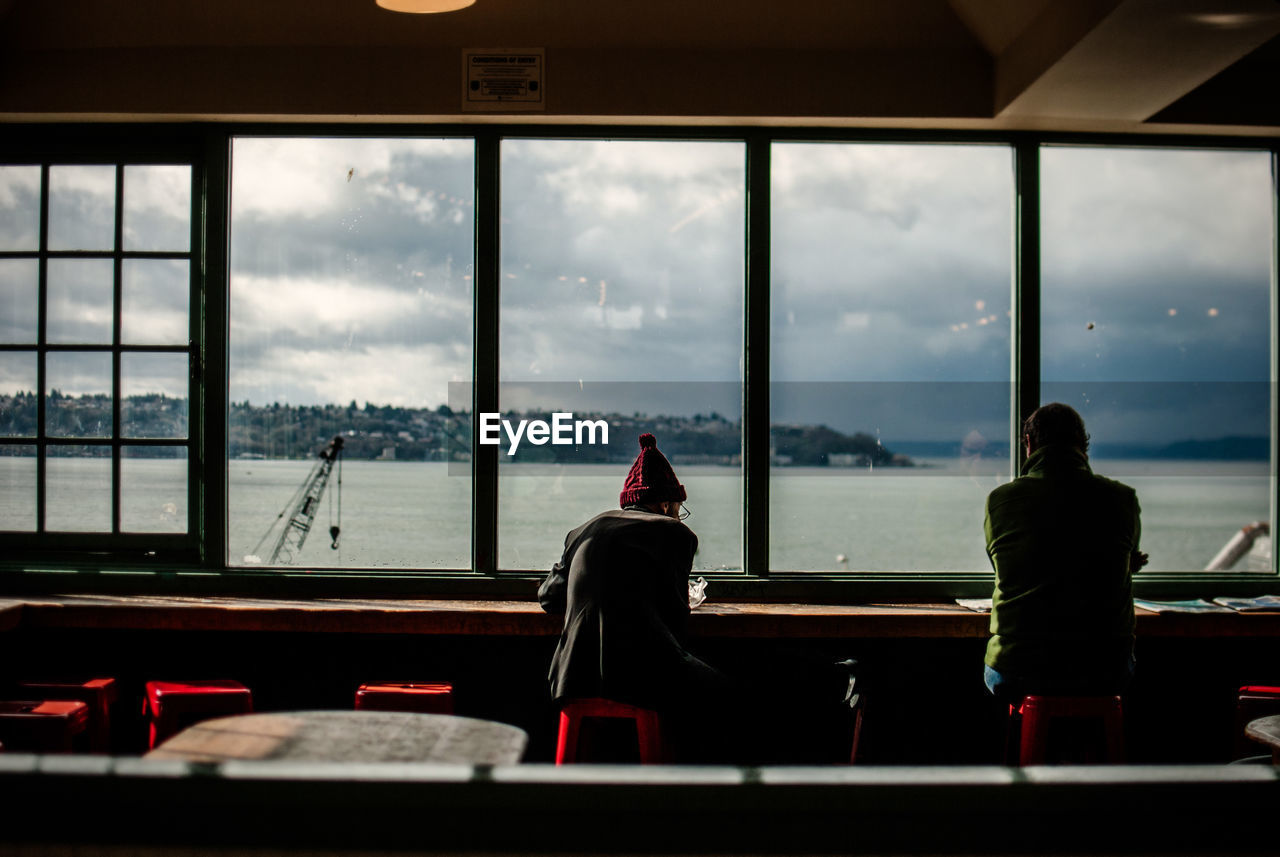 Rear view of men sitting by window at restaurant