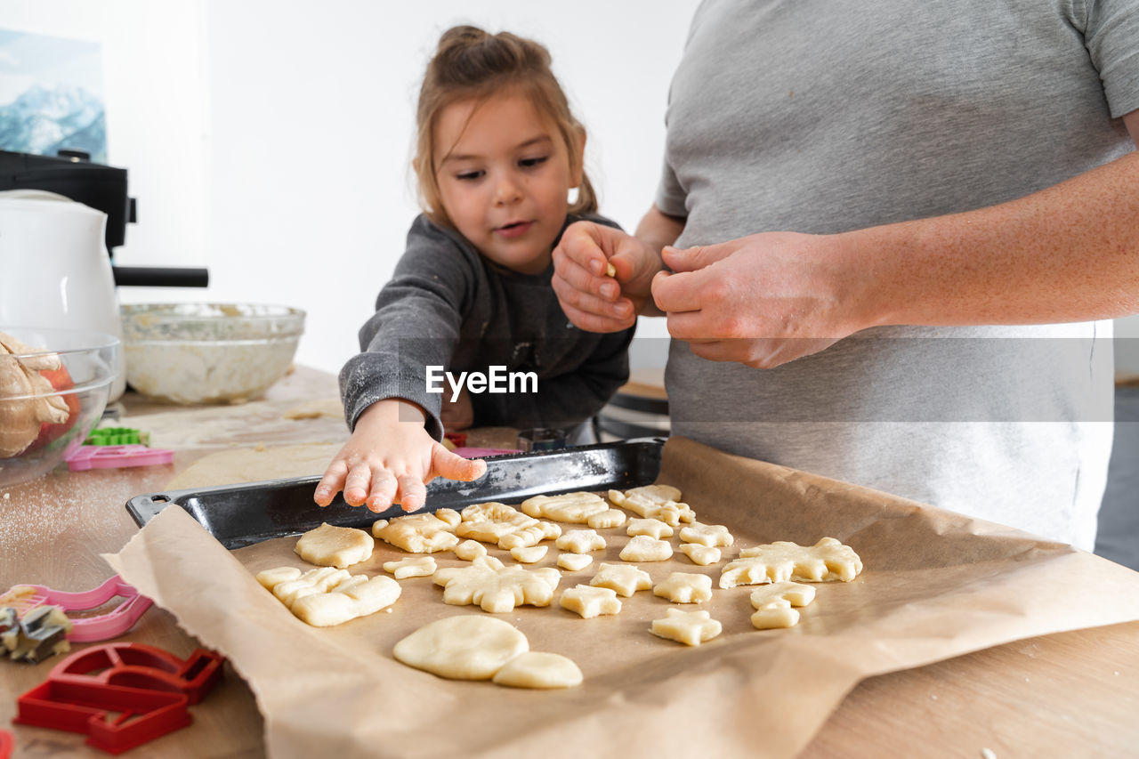 Midsection of father with daughter preparing cookies at home