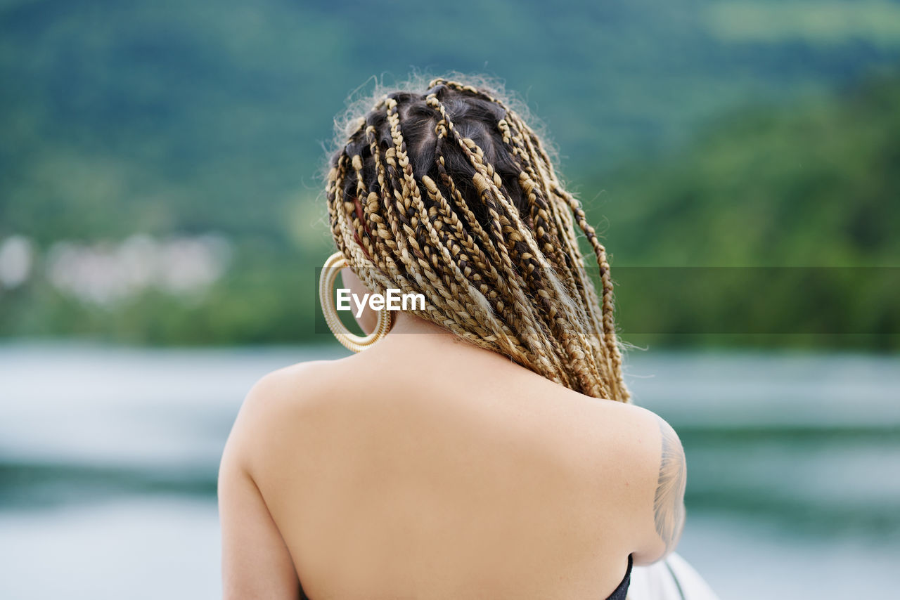 Back of a young woman with braided blonde hair and the water of a reservoir in the background