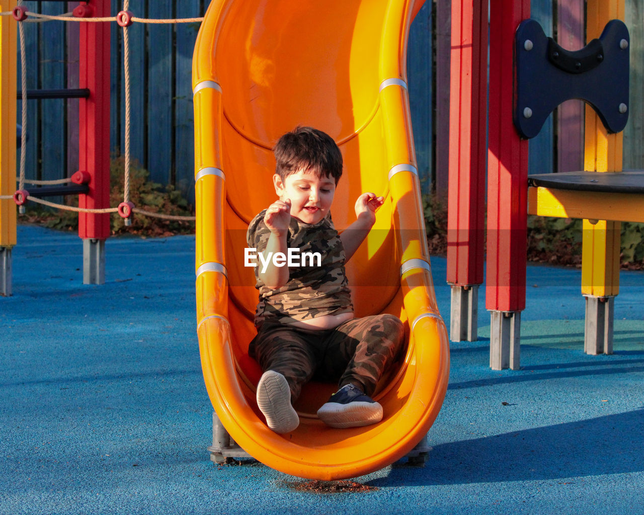 Boy sitting on slide at playground