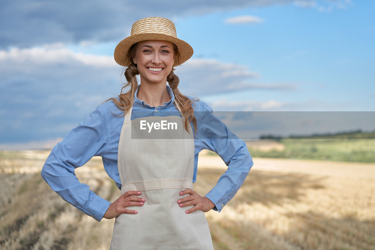 PORTRAIT OF A SMILING YOUNG WOMAN WEARING HAT